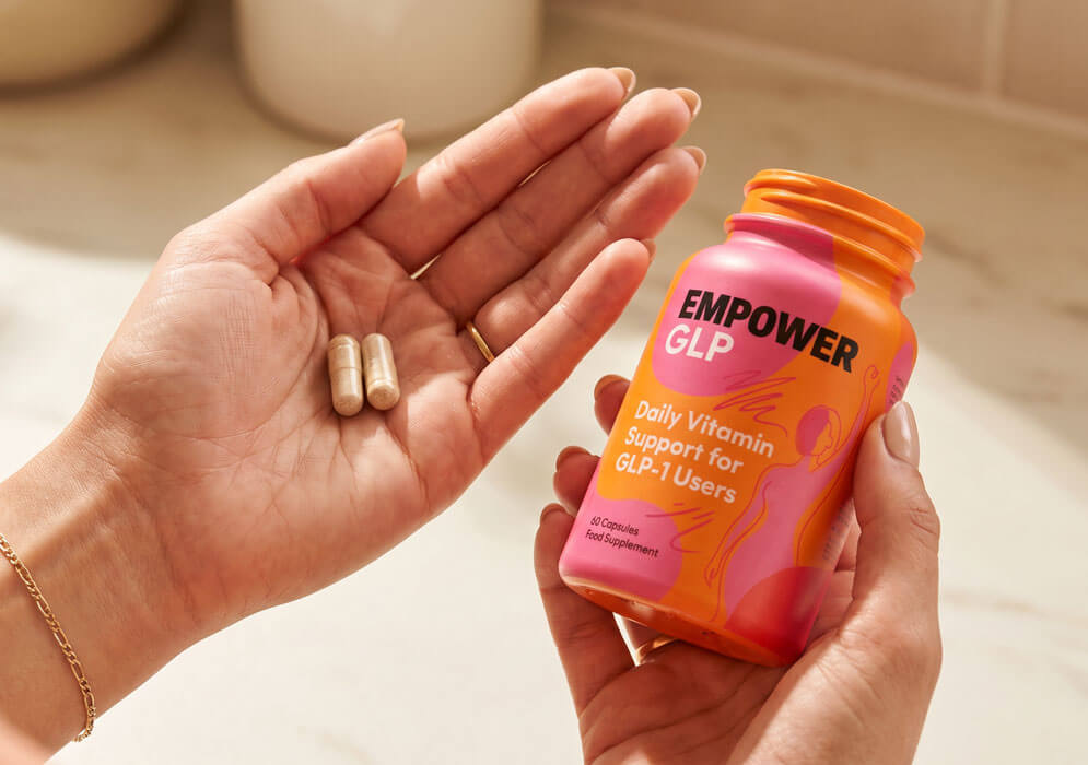 Hands holding the EmpowerGLP™ bottle next to two capsules