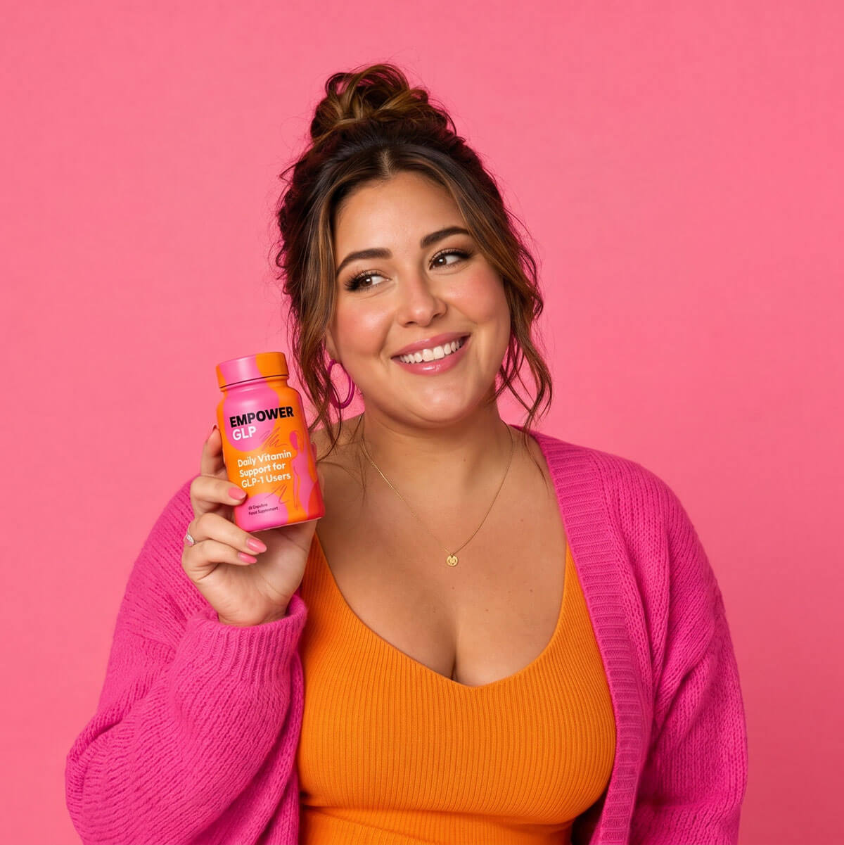 Smiling woman in a pink cardigan holding the EmpowerGLP™ bottle